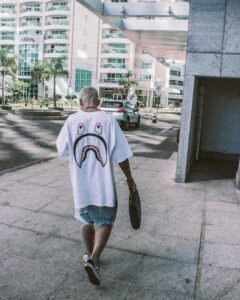 Man in streetwear walking in urban area with buildings in the background.