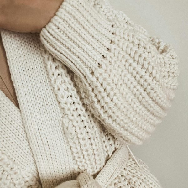 Close-up of a cozy handmade white knitted sweater showcasing texture and pattern.