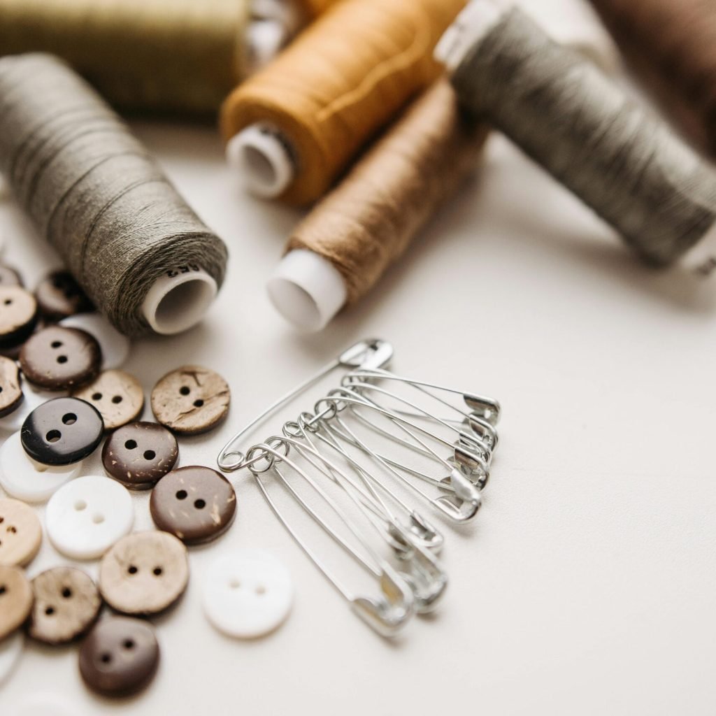 Close-up of sewing threads, buttons, and safety pins on a light background, perfect for craft projects.